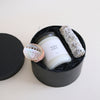 Candle in a black container with decorative elements on a light background